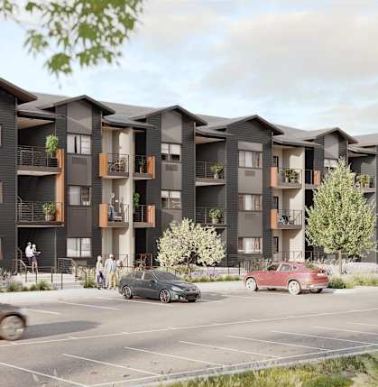 A row of modern apartment buildings with cars parked in front.