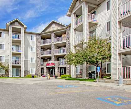 The front of the beige apartment homes with a red sign over the doorway at the Pointe at Applewood Apartment Homes. 