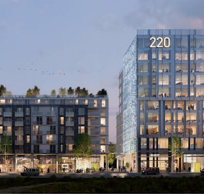 A modern building with the number 220 on it is lit up at dusk.
