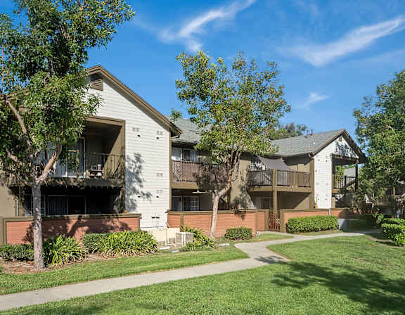 A pool surrounded by palm trees and umbrellas at The Kitt at Warner Center Apartments, Woodland Hills 91303