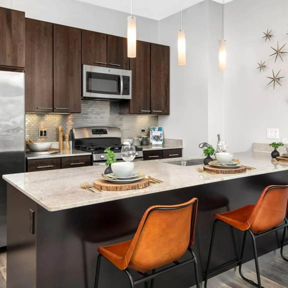 a kitchen with a large island with three orange chairs in front of it