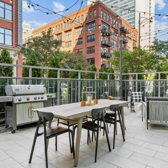 a patio with a table and chairs and a grill