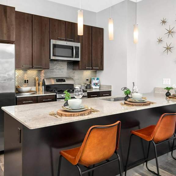 a kitchen with a large island with three orange chairs in front of it