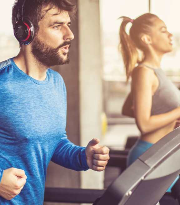 A man and a woman are working out on treadmills in a gym.