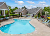 Thumbnail 6 of 8 - A swimming pool surrounded by lounge chairs and a building in the background.