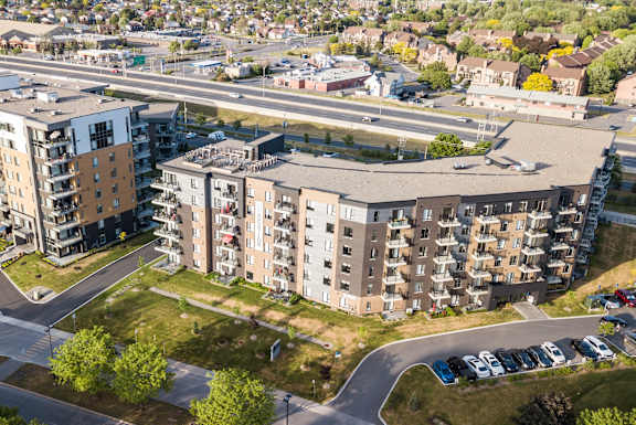 an aerial view of an apartment complex with a highway in the background