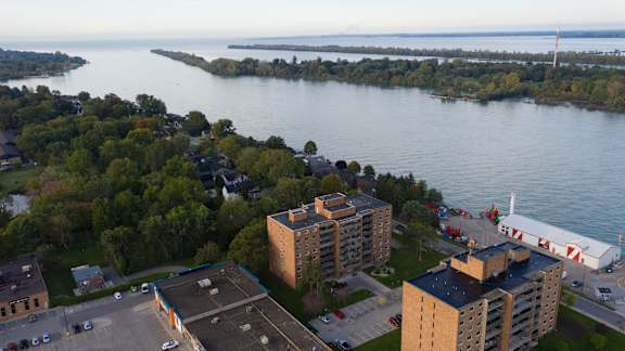 A view of a lake with buildings and trees in the foreground.