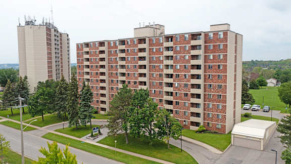 an aerial view of an apartment building with trees and a road