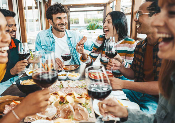 a group of people laughing and drinking wine at a table at Junction Central, Seattle