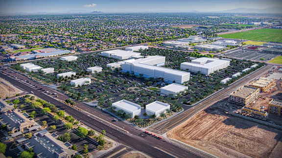A large white building is surrounded by a parking lot and other buildings.at The Residences at The Gilmore in Gilbert, AZ