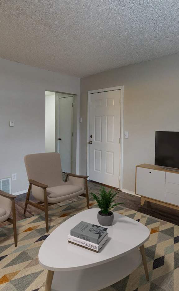 Living room with a sofa, two chairs, a coffee table, and a television.