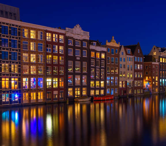 A beautiful cityscape at night with buildings reflecting in the water.