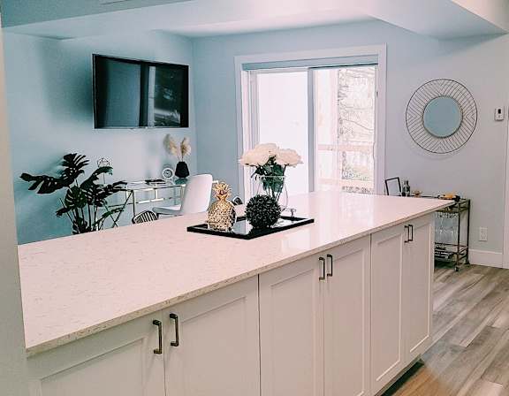 A kitchen with a white counter and bar stools.