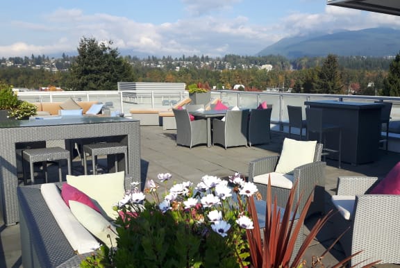 a rooftop patio with tables and chairs and a view of the mountains
