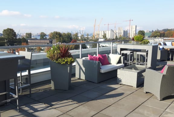 a roof deck with furniture and a city in the background