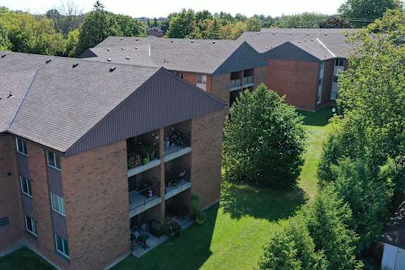 an aerial view of a building with a green lawn and trees