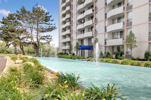 A fountain in the middle of a grassy area in front of a building.