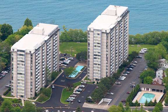 Two identical buildings are situated next to each other with a pool in the middle.