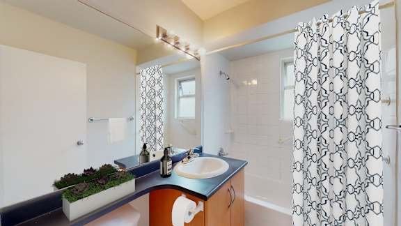 A bathroom with a sink, mirror, and shower curtain.