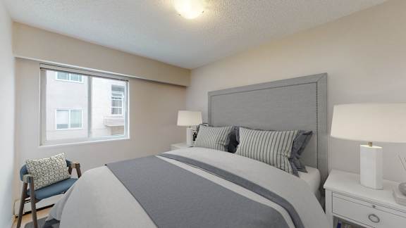 A bedroom with a large bed and a chair by the window.