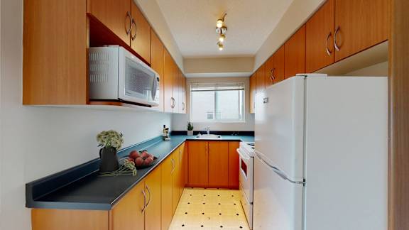 A kitchen with a white refrigerator and wooden cabinets.
