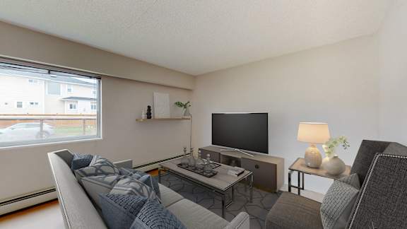 A living room with a grey couch, a black television, and a small table with a lamp on it.