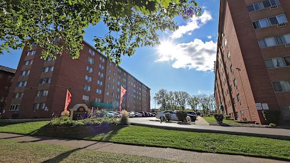 A sunny day at a brick apartment complex with a car parked in the driveway.