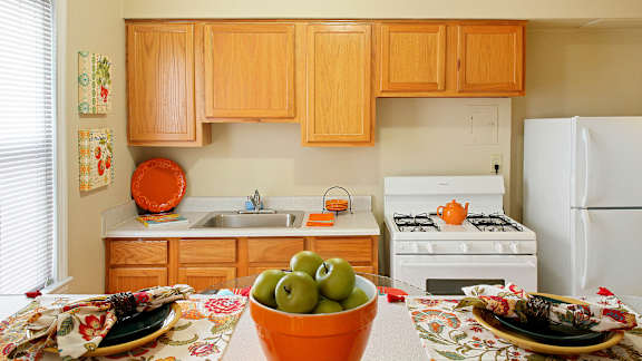 A kitchen with wooden cabinets and a white stove top oven.