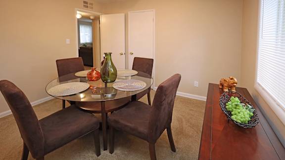 A dining table with chairs and a bowl of grapes on a table.