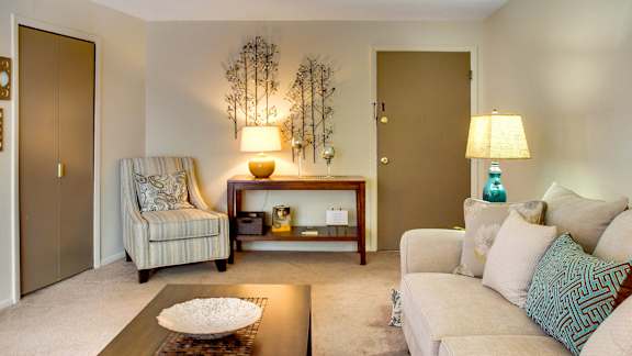 A living room with a striped chair and a couch.