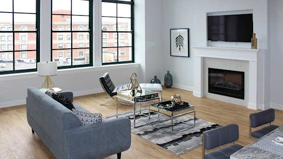 A living room with a grey couch, a coffee table, a fireplace, and a TV.