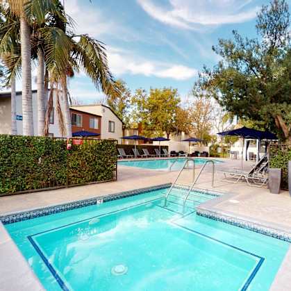 a swimming pool with trees and a building in the background at Avante Apartments, Ontario, California, 91764