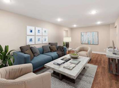 A living room with a blue couch, a grey coffee table, and a white chair.