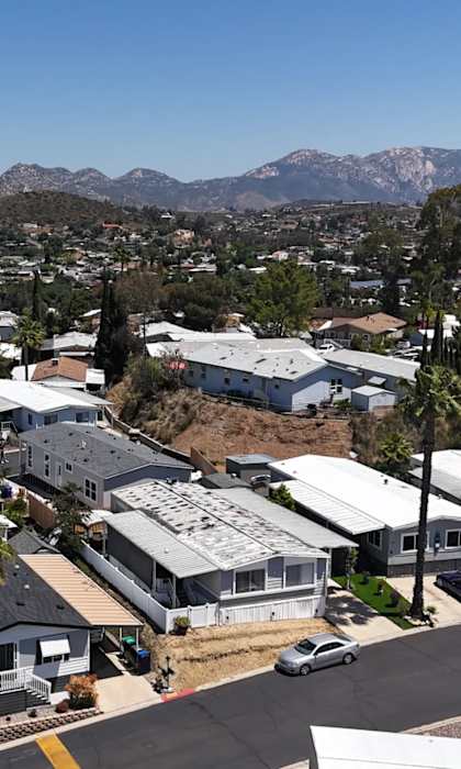 A residential area with houses and a mountain range in the background.
