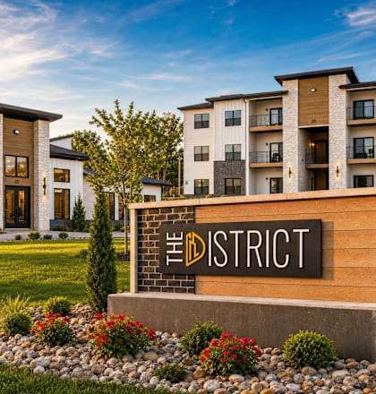 The District apartment complex is surrounded by a well-manicured lawn and trees.