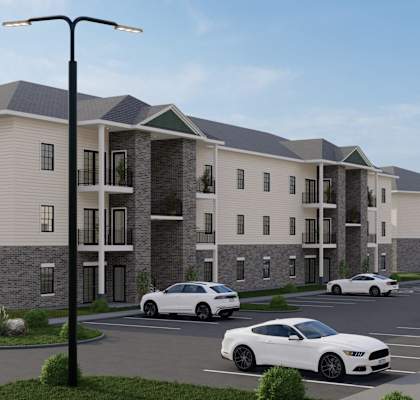 A modern apartment complex with cars parked in the driveway.