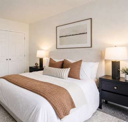 A bedroom with a large bed and a painting on the wall.