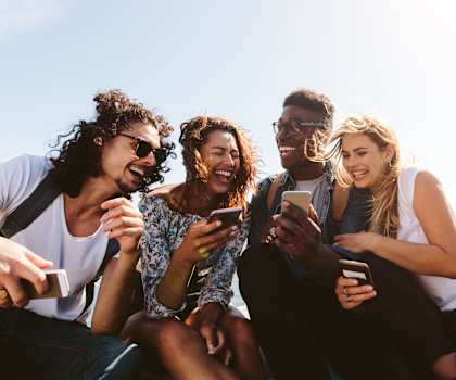 Four friends are sitting together and looking at their phones at Overlook Club Apartments, Cummings, GA, 30040