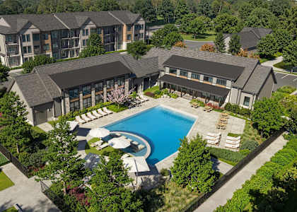 A large building with a pool and tennis court in front.