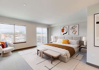 A well-lit bedroom with a large bed and a window overlooking the city.