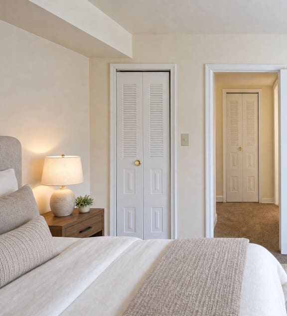 A bedroom with a bed, two doors, and a plant.
