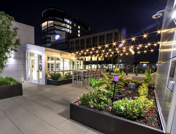 A building with a lit up entrance and a planter box in front.