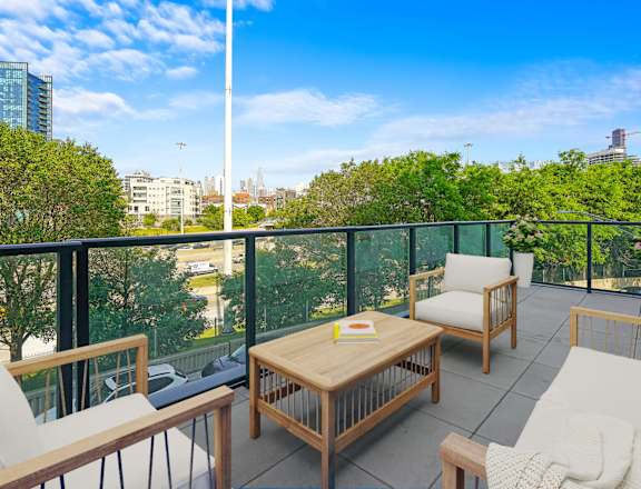 A balcony with white chairs and a wooden table.