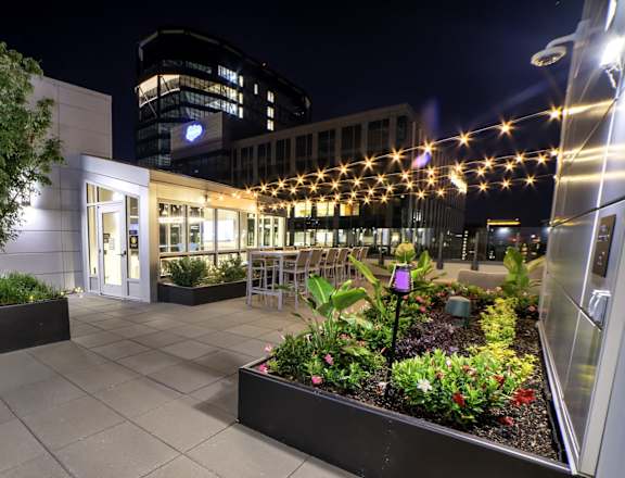 A building with a lit up entrance and a planter box in front.