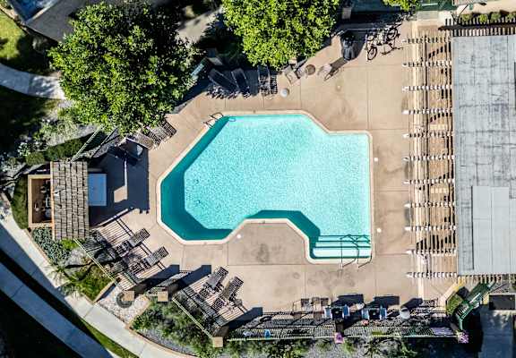 An aerial view of a pool surrounded by a deck and trees. at Heritage Park, Rialto California