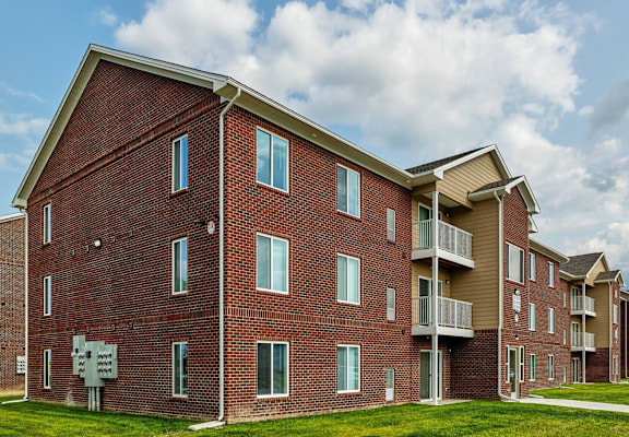 A red brick apartment building with a white sign in front.