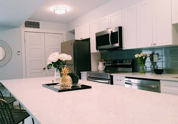 A kitchen with a white countertop and black chairs.