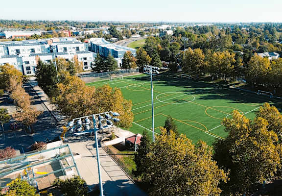 A view of a school campus with a sports field and trees.