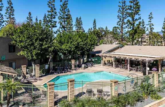 A pool surrounded by a fence and trees. at Heritage Park, Rialto, CA 92376