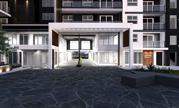 A modern building entrance with a stone pathway leading to a white doorway.